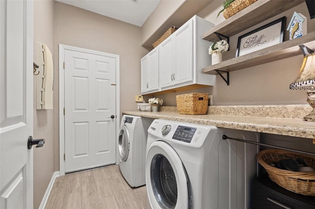 laundry room featuring separate washer and dryer, light hardwood / wood-style flooring, and cabinets