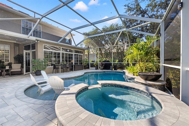 view of pool with an in ground hot tub, glass enclosure, and a patio area