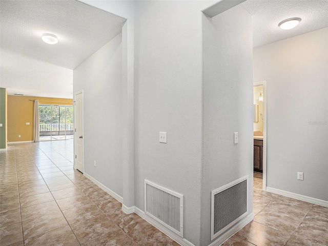 hallway featuring light tile patterned floors and a textured ceiling