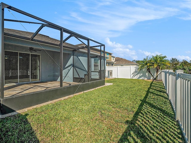 view of yard with ceiling fan and a lanai