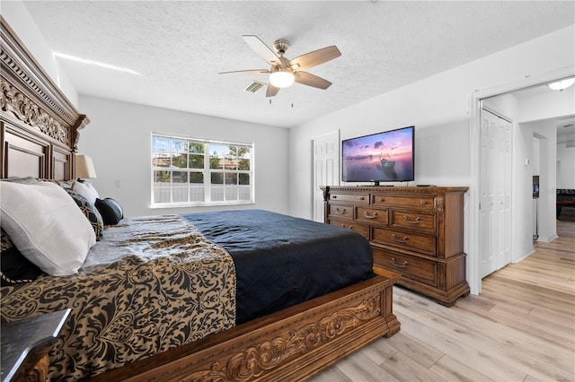 bedroom with ceiling fan, light hardwood / wood-style floors, and a textured ceiling