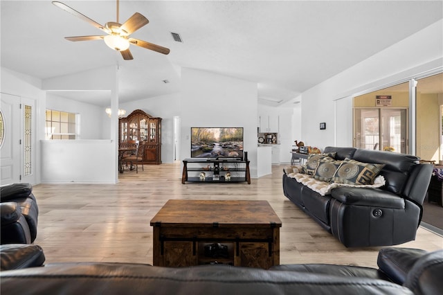 living room featuring ceiling fan with notable chandelier, vaulted ceiling, and light hardwood / wood-style flooring