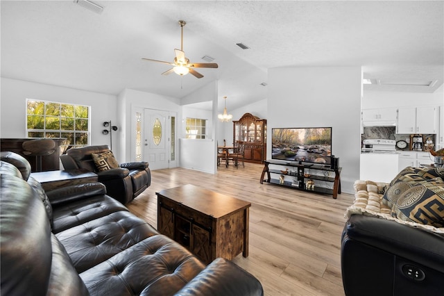 living room with ceiling fan with notable chandelier, vaulted ceiling, light hardwood / wood-style flooring, and a textured ceiling