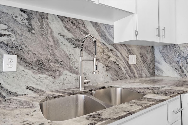 kitchen featuring sink, dark stone countertops, white cabinets, and backsplash