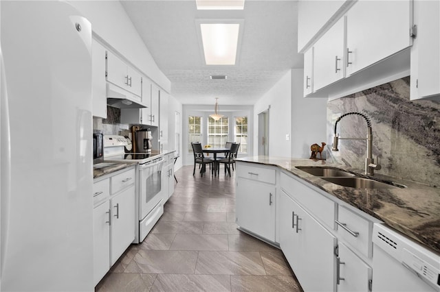 kitchen with decorative light fixtures, sink, dark stone countertops, white cabinets, and white appliances