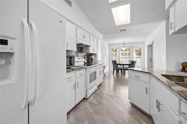 kitchen with sink, white appliances, white cabinetry, a textured ceiling, and decorative light fixtures