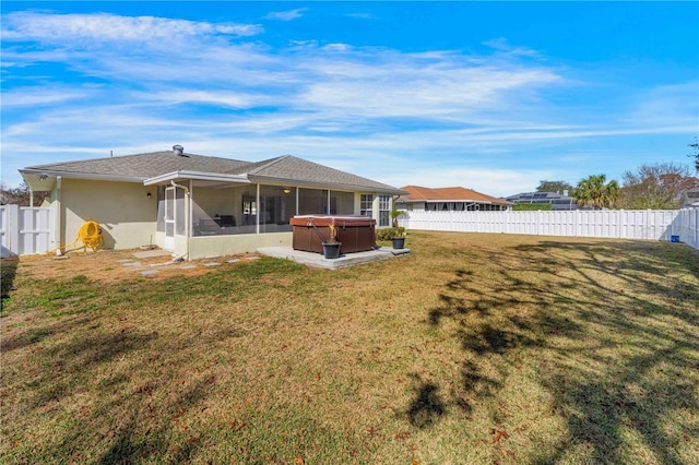 rear view of house with a hot tub, a sunroom, and a lawn