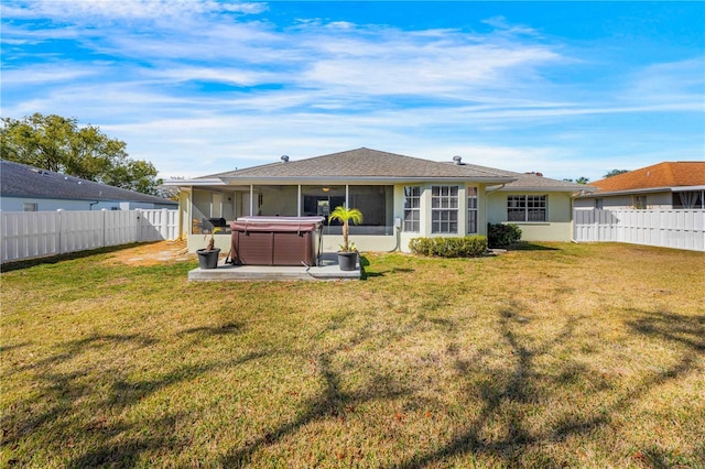 rear view of property with a yard, a hot tub, and a sunroom