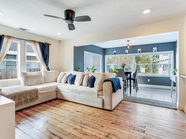 living room featuring ceiling fan, a textured ceiling, a healthy amount of sunlight, and light wood-type flooring