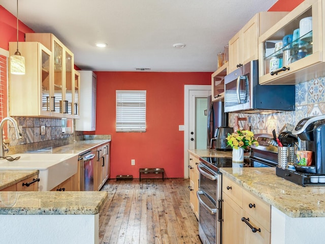 kitchen featuring sink, kitchen peninsula, light brown cabinets, and decorative light fixtures