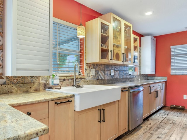 kitchen featuring light brown cabinetry, sink, stainless steel dishwasher, pendant lighting, and decorative backsplash