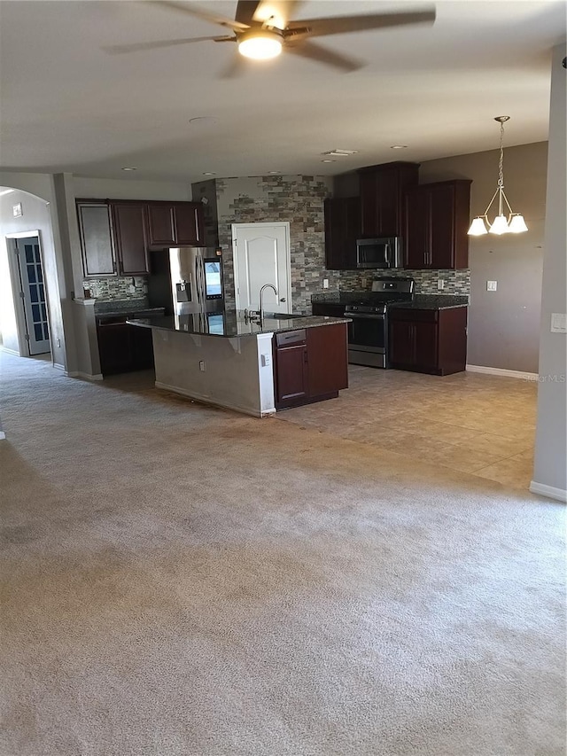 kitchen with pendant lighting, dark brown cabinetry, stainless steel appliances, and a center island with sink