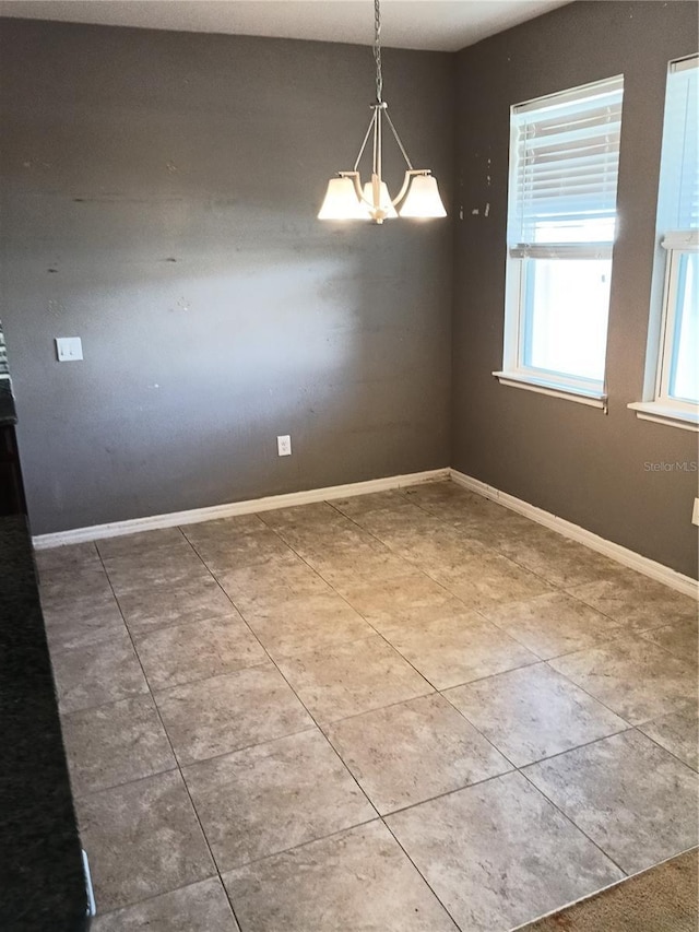 spare room featuring tile patterned flooring and a notable chandelier