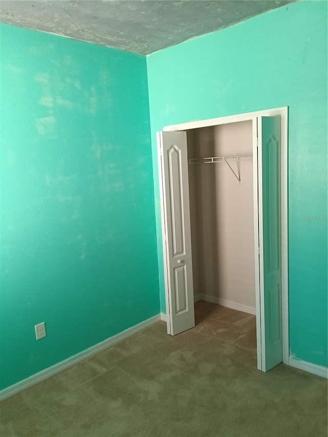 unfurnished bedroom with light carpet and a closet