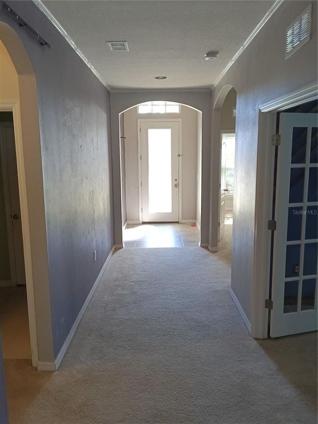 hallway with crown molding and light colored carpet