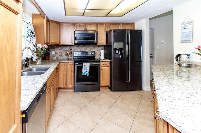 kitchen featuring sink, light tile patterned floors, appliances with stainless steel finishes, backsplash, and light stone counters