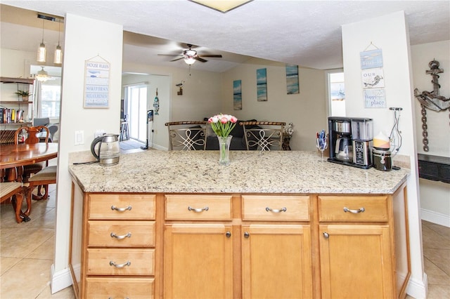 kitchen with light tile patterned flooring, ceiling fan, and light stone countertops