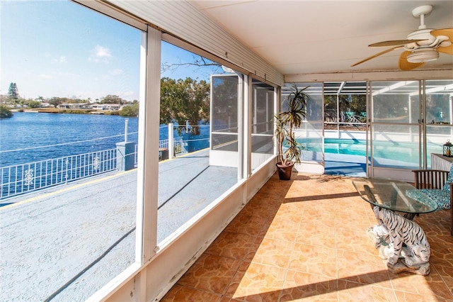 sunroom featuring ceiling fan and a water view