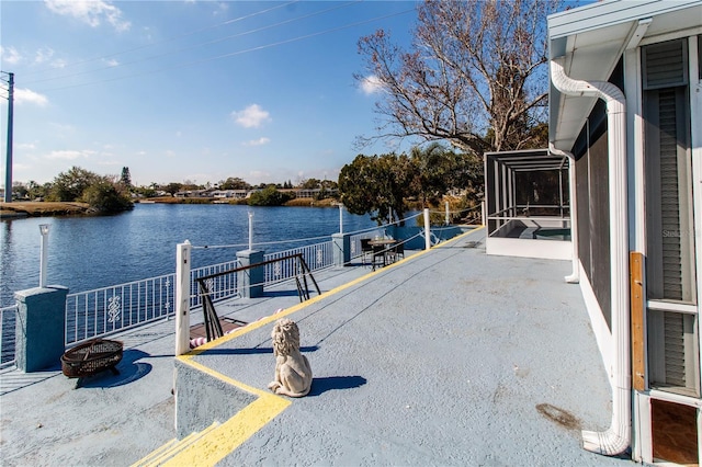 view of dock with a water view, an outdoor fire pit, and a patio