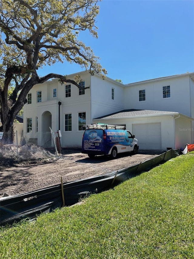 view of front of property featuring an attached garage, dirt driveway, and stucco siding