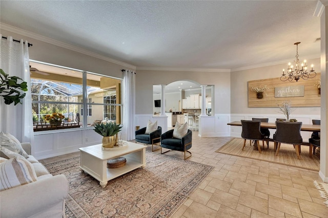 living room featuring decorative columns, ornamental molding, and a textured ceiling