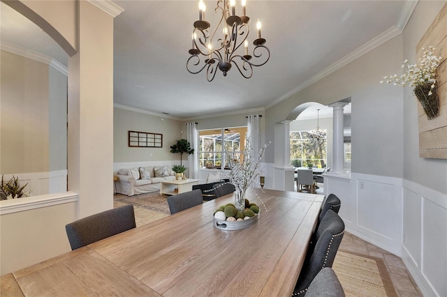 dining space featuring crown molding, a chandelier, and decorative columns