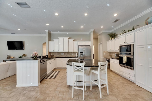 kitchen with a kitchen bar, kitchen peninsula, a kitchen island, stainless steel appliances, and white cabinets