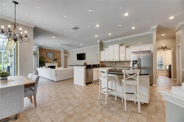 kitchen with stainless steel appliances, a center island, white cabinets, a kitchen bar, and decorative light fixtures