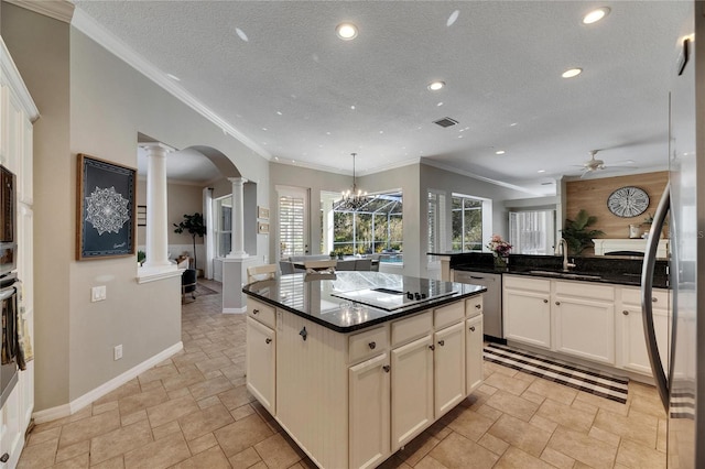 kitchen featuring a kitchen island, decorative light fixtures, decorative columns, sink, and black electric stovetop