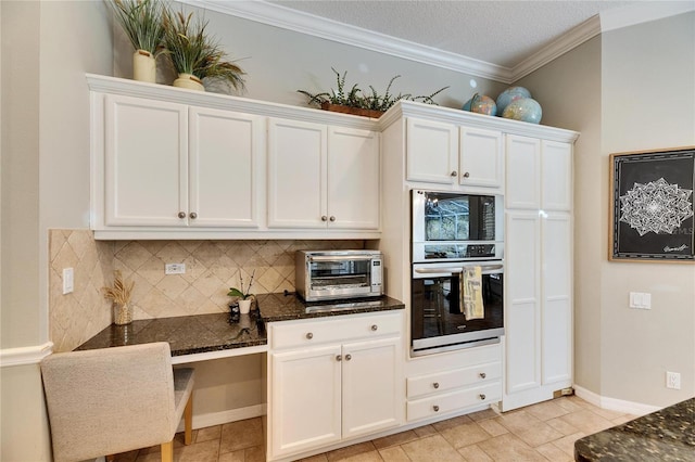 kitchen featuring tasteful backsplash, white cabinetry, oven, dark stone counters, and crown molding