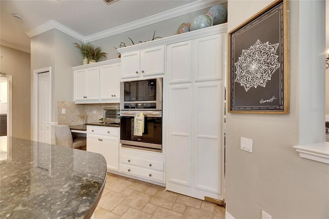 kitchen with white cabinetry, black microwave, dark stone countertops, oven, and decorative backsplash