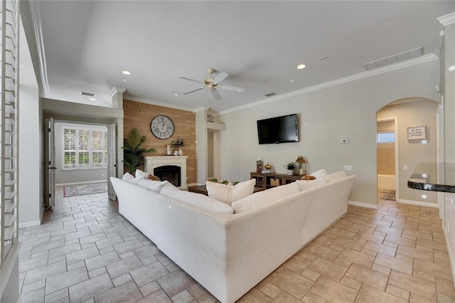 living room with ceiling fan, ornamental molding, a textured ceiling, and wood walls