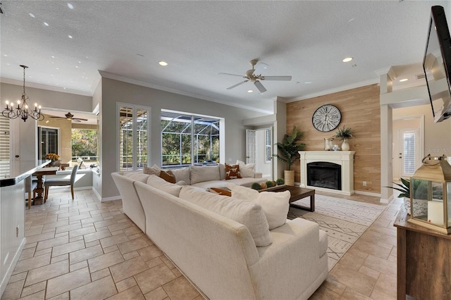 living room with ornamental molding, ceiling fan with notable chandelier, a textured ceiling, and wood walls