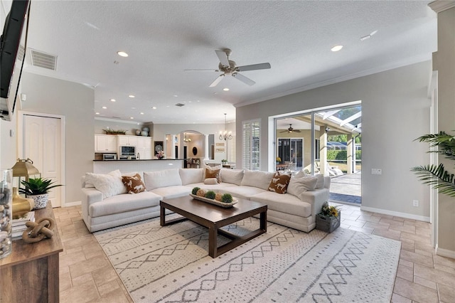 living room featuring ceiling fan with notable chandelier, ornamental molding, and a textured ceiling