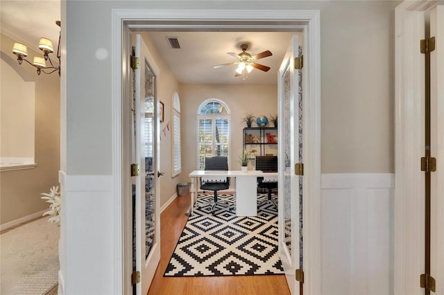 corridor with an inviting chandelier and light hardwood / wood-style floors