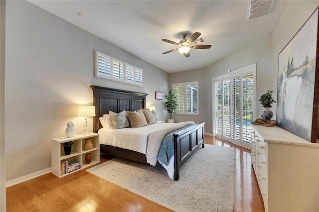 bedroom with hardwood / wood-style floors, access to outside, a textured ceiling, and ceiling fan