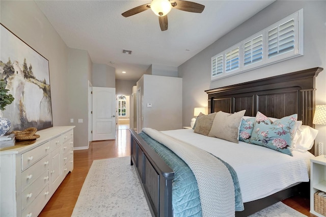 bedroom with ceiling fan, a textured ceiling, and light hardwood / wood-style floors