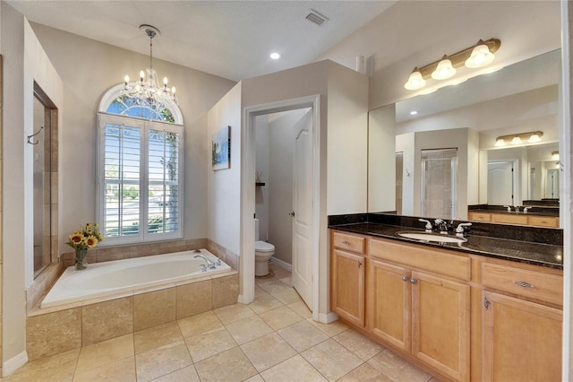 bathroom with tile patterned flooring, an inviting chandelier, vanity, a relaxing tiled tub, and toilet