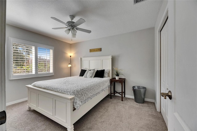 carpeted bedroom with ceiling fan, a textured ceiling, and a closet