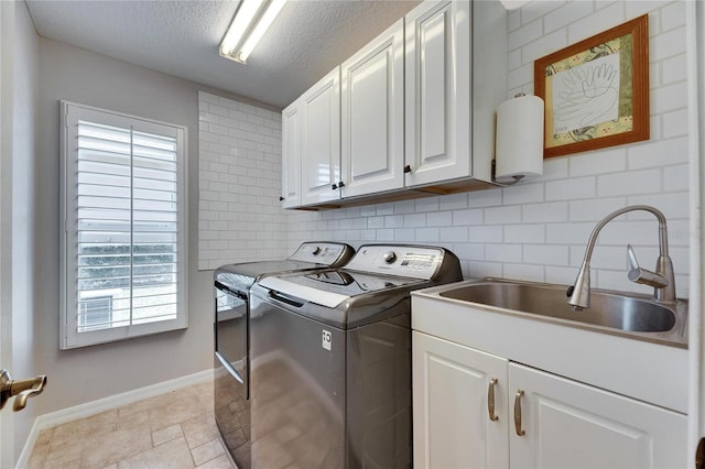 clothes washing area featuring cabinets, sink, washer and dryer, and a textured ceiling