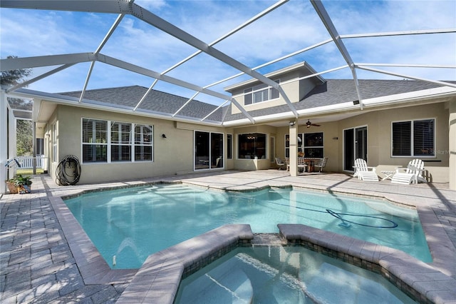 view of pool featuring an in ground hot tub, ceiling fan, glass enclosure, and a patio