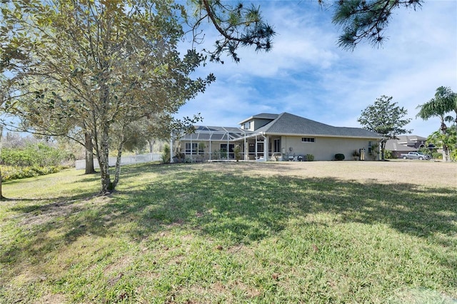 rear view of property featuring a lanai and a lawn