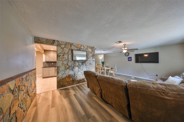 living room with ceiling fan, light hardwood / wood-style flooring, and a textured ceiling