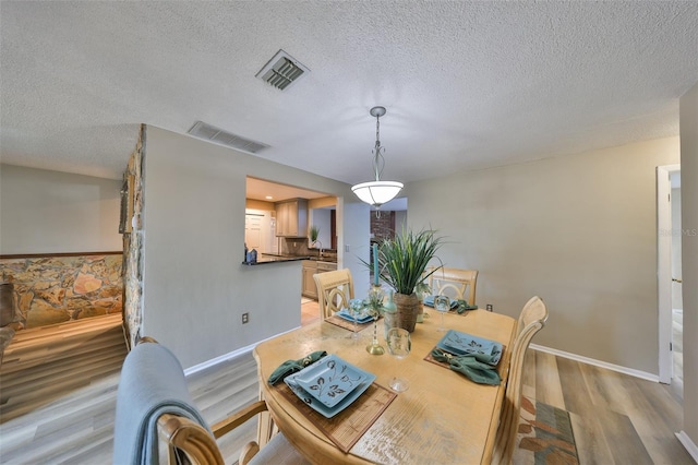 dining area featuring sink, light hardwood / wood-style floors, and a textured ceiling