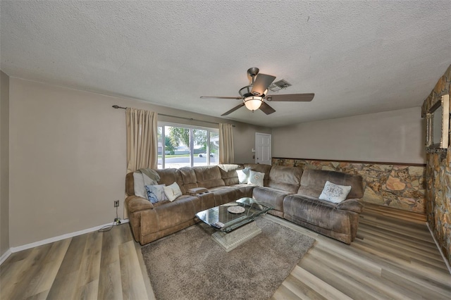 living room featuring ceiling fan, a textured ceiling, and light wood-type flooring