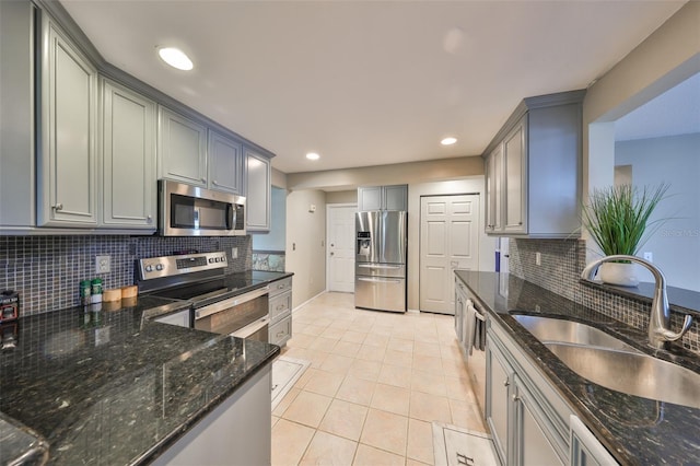 kitchen featuring appliances with stainless steel finishes, sink, decorative backsplash, and dark stone counters