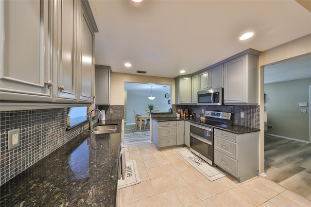 kitchen featuring stainless steel appliances, sink, dark stone countertops, and light tile patterned floors