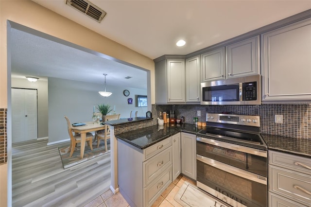 kitchen featuring gray cabinetry, decorative light fixtures, stainless steel appliances, and decorative backsplash