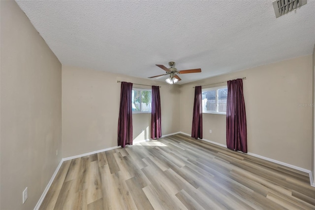 empty room featuring ceiling fan, light hardwood / wood-style floors, and a textured ceiling