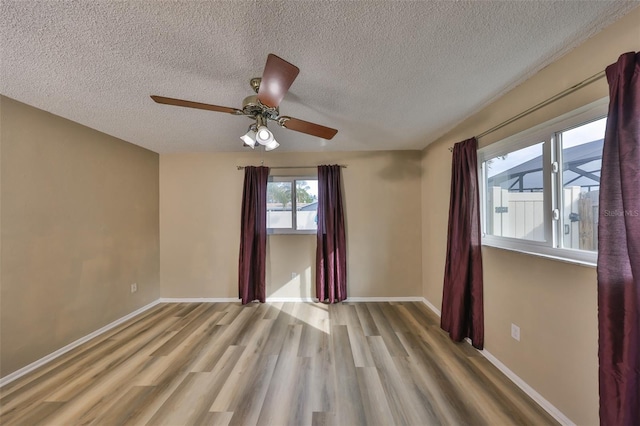 empty room with a textured ceiling and light hardwood / wood-style floors